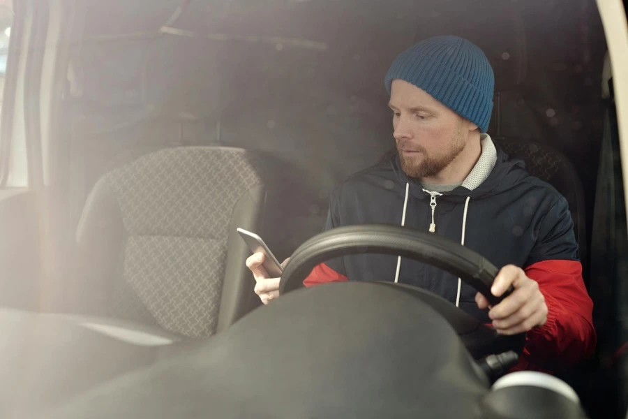 車の前でスマートフォンを操作している人の手元