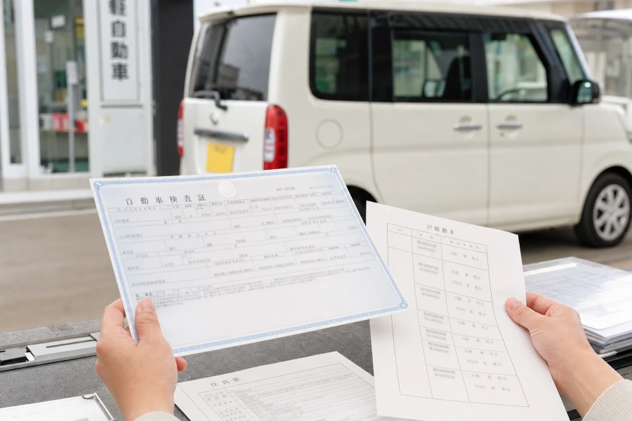 軽自動車の車検証と相続関係書類を窓口前で確認する様子